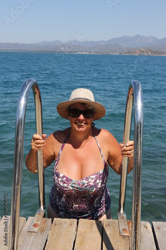 A buxom mature english lady getting out of the sea using ladders on the jetty while on vacation in turkey 2017