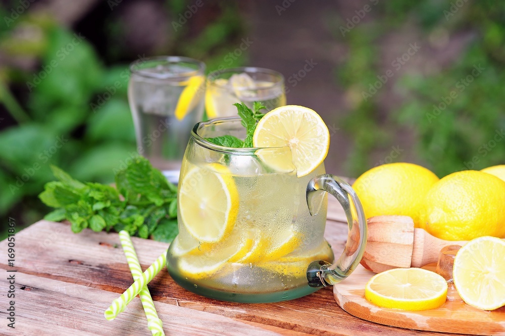 Fototapeta premium Cold summer drinks in the garden, cold lemonade with lemon and mint