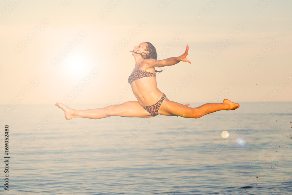 Girl gymnast flies over the water in the sea. Girl gymnast flies over the water in the sea.