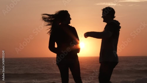 Slow motion couple kissing at the beach during sunset.