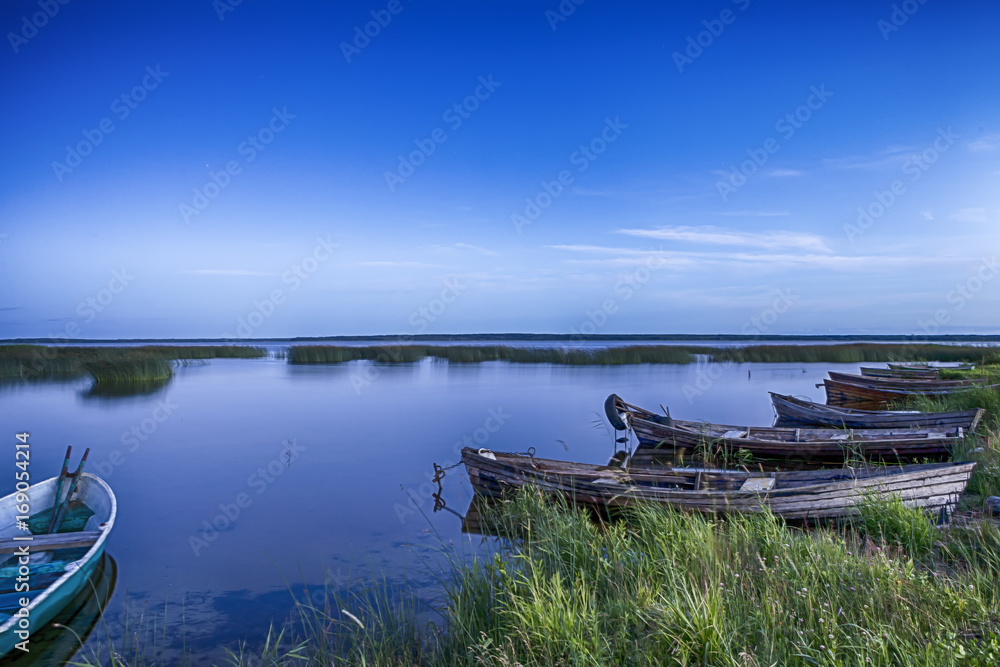 Scenic Destinations. Line of Boats on Water Placed in Belarussian National Park Braslav Lakes at Sunset during Summer Time.