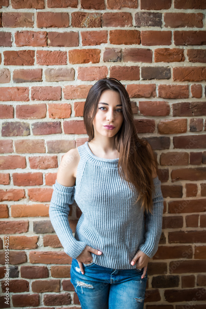 Serious brunette woman against red brick wall closeup photo