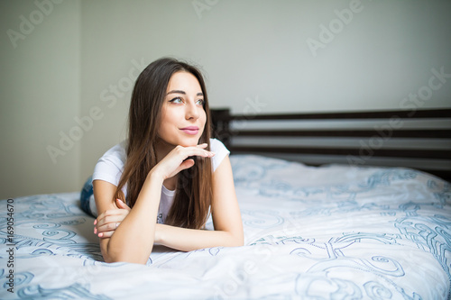 Portrait of a dreaming beautiful young woman lying on bed photo