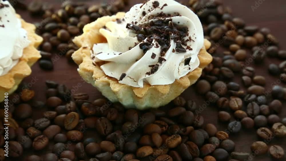 Morning breakfast. Cakes with whipped cream lie on the table next to coffee beans. Close-up. Full hd shot with dolly from right to left Morning breakfast. Cakes with whipped cream lie on the table next to coffee beans. Close-up. Full hd shot with dolly from right to left