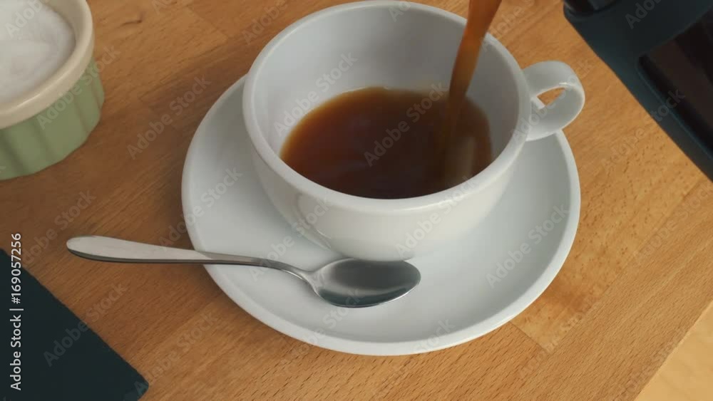 Dolly panning shot of Coffee being poured into a white cup from a cafetière on a wooden breakfast table. Dolly panning shot of Coffee being poured into a white cup from a cafetière on a wooden breakfast table.