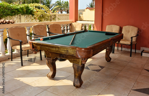 Beautiful photo of stylish pool table with a cue and billiard balls on a nice patio. Snooker