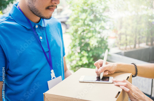 Woman appending signature after accepting a delivery of boxes from deliveryman photo