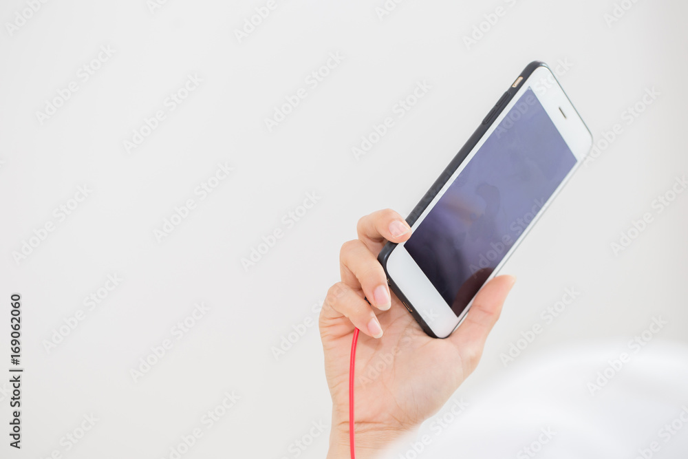 Hand holding smartphone with ear phone line,Copy space Hand holding smartphone with ear phone line,Copy space