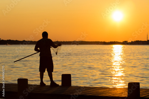 Man crabbing fishing during sunset on the boardwalk