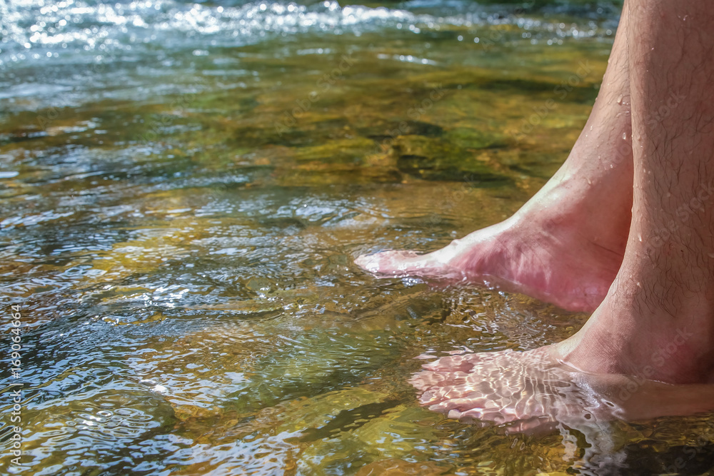 Dipping feet in cold lake water on summer