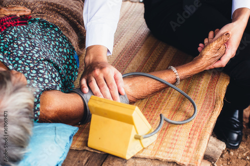 Canvas Print Male Doctor listening heart beat and breathing of Elderly Woman with Stethoscope with First Aid Medical Box