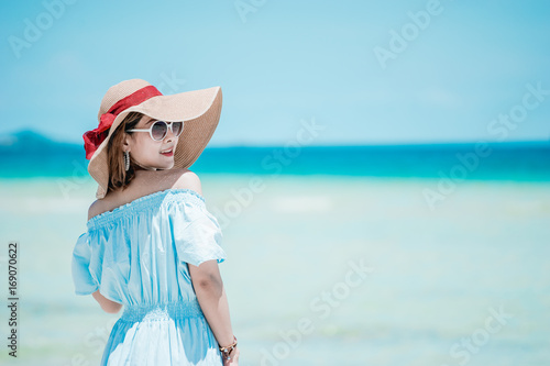Young woman wearing Hawaiian with hat and sunglasses is happy when they go to the beach for a holiday.