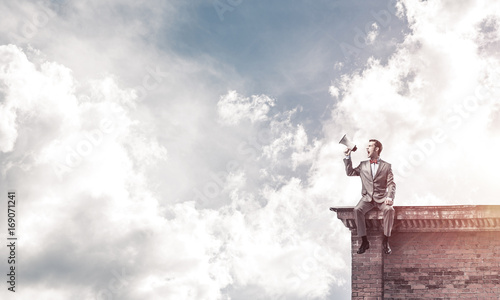 Businessman or manager on building roof announcing something in 