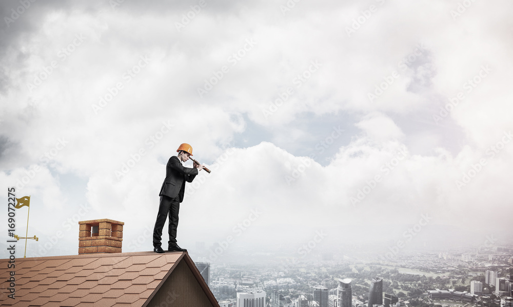 Engineer man standing on roof and looking in spyglass. Mixed med Engineer man standing on roof and looking in spyglass. Mixed med