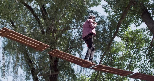 Wallpaper Mural Male teenager walks on rope trail at adventure park 4k video. Young climber enjoying extreme adventure Torontodigital.ca