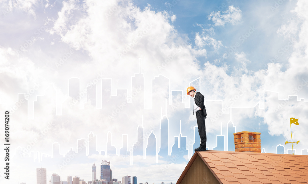 Engineer man standing on roof and looking down. Mixed media Engineer man standing on roof and looking down. Mixed media