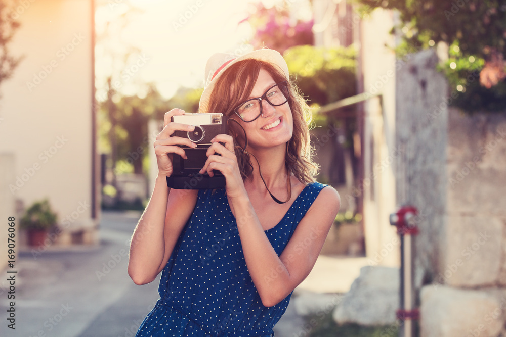 Cute young female holding a retro-styled camera outdoors.