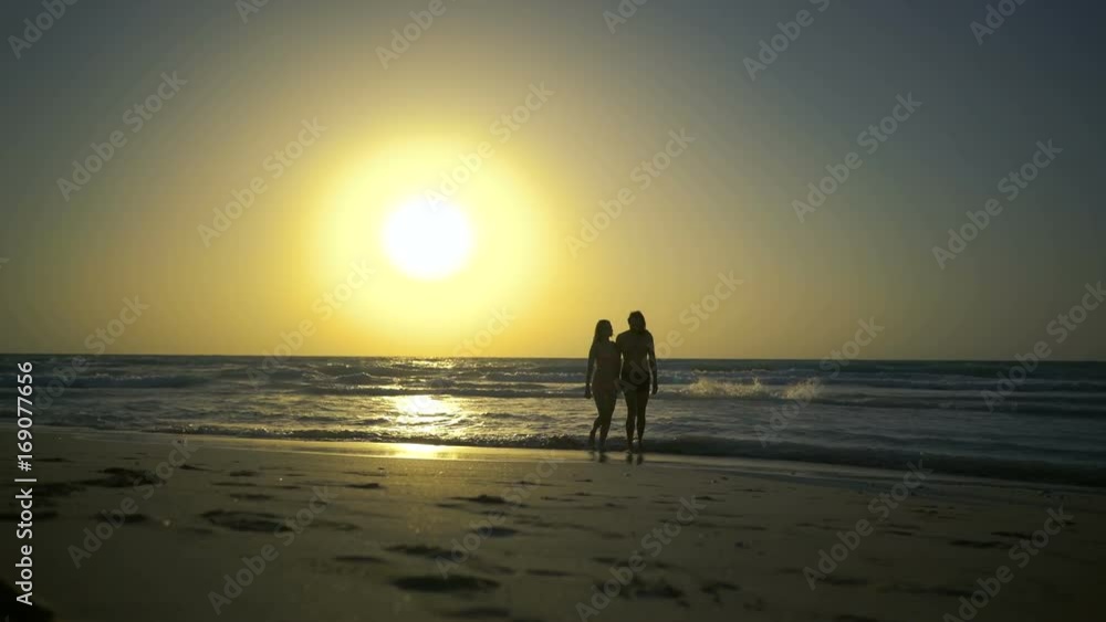 Romantic couple is falling in love on the beach in water. Man with woman is holding hands and walking along the golden sandy beach. Two hipster in love, walks, relaxes at amazing beautilful sunset Romantic couple is falling in love on the beach in water. Man with woman is holding hands and walking along the golden sandy beach. Two hipster in love, walks, relaxes at amazing beautilful sunset