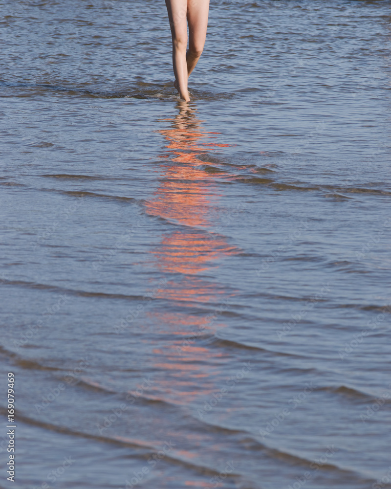 Woman walking water on the summer beach.