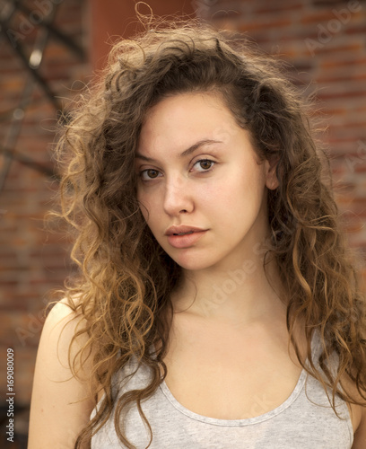 Young girl with a curly hair without makeup pose indoors