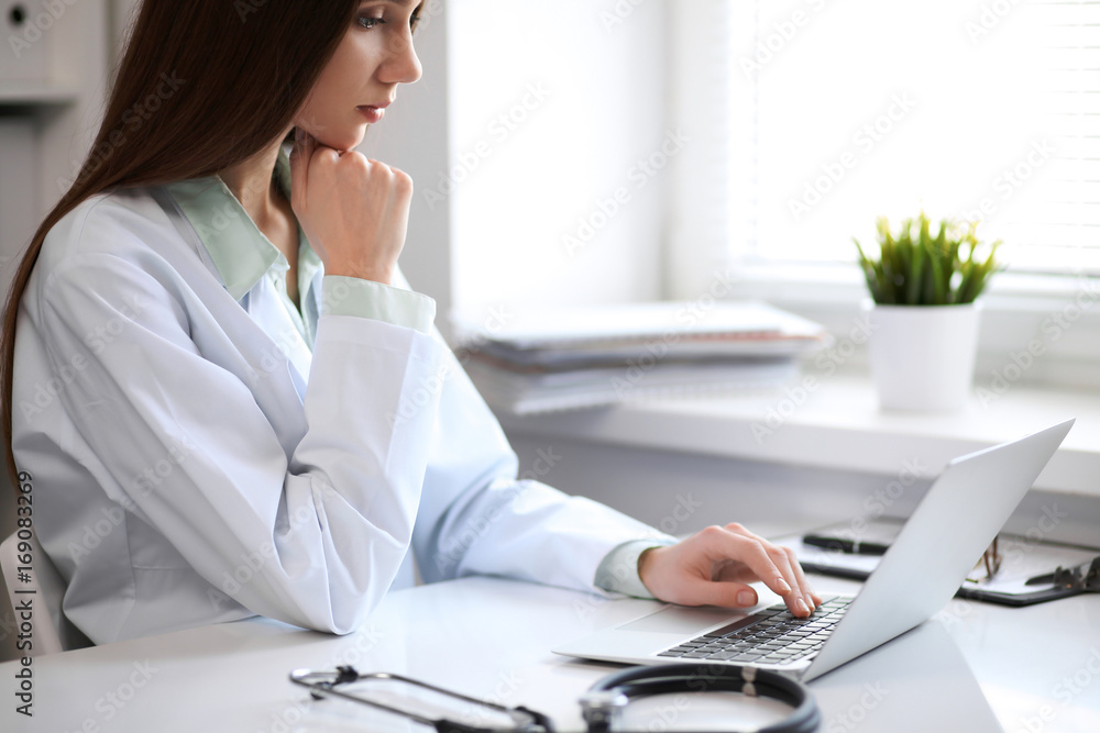 Female doctor brunette sitting at the table near the window in hospital Female doctor brunette sitting at the table near the window in hospital