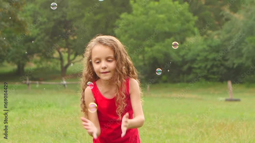 Girl playing catch soap bubbles on the garden. Slow motion. Close up Girl playing catch soap bubbles on the garden. Slow motion. Close up