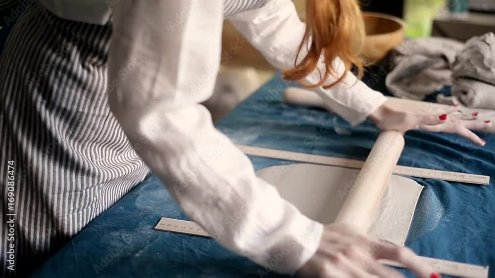 master shapes pottery on a blue canvas. Creative process. Gives shape to your product.Spread the clay with a rolling pin master shapes pottery on a blue canvas. Creative process. Gives shape to your product.Spread the clay with a rolling pin