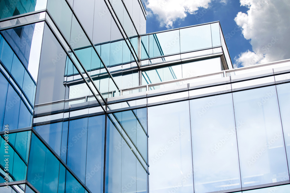 Obraz premium Blue sky and clouds reflecting in windows of modern office building