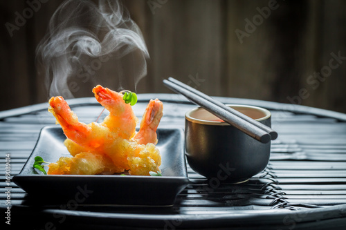 Golden shrimp in tempura with red sauce on dark background