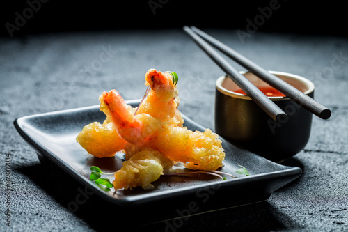 Hot shrimp in tempura with red sauce on black rock