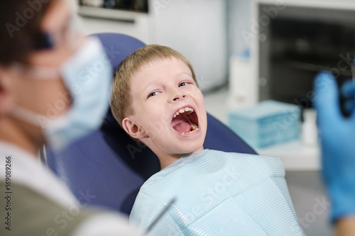 Male dentist examines the teeth of the patient cheerful boy. photo