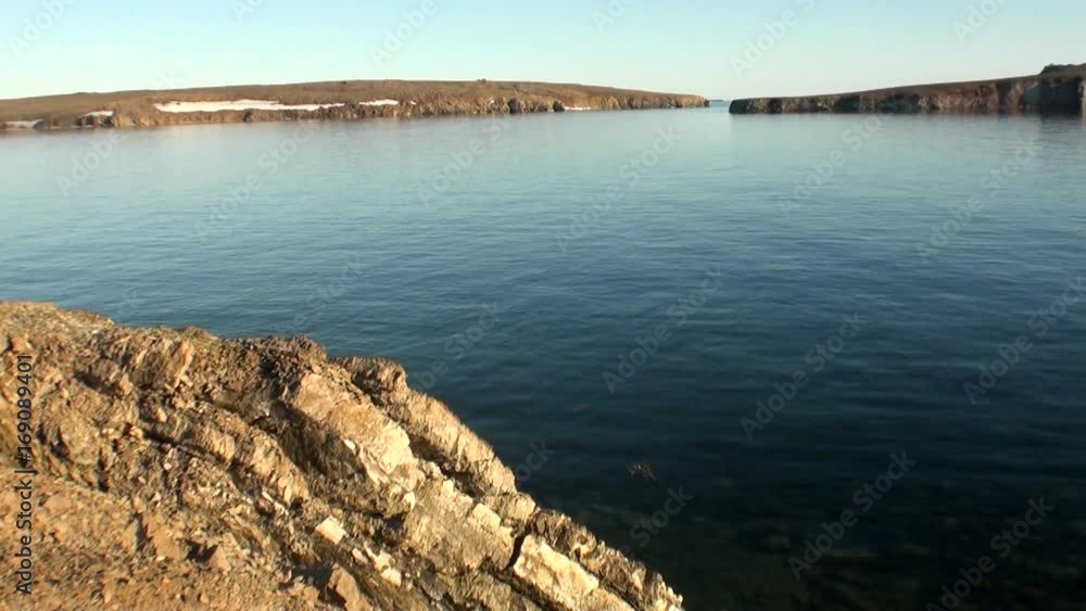 Snow on coast and surface clean clear water of Arctic Ocean on New Earth. Beautiful landscape of wild nature. Quiet and calm ecotourism in Russia. Panorama of way to cold wilderness. Snow on coast and surface clean clear water of Arctic Ocean on New Earth. Beautiful landscape of wild nature. Quiet and calm ecotourism in Russia. Panorama of way to cold wilderness.