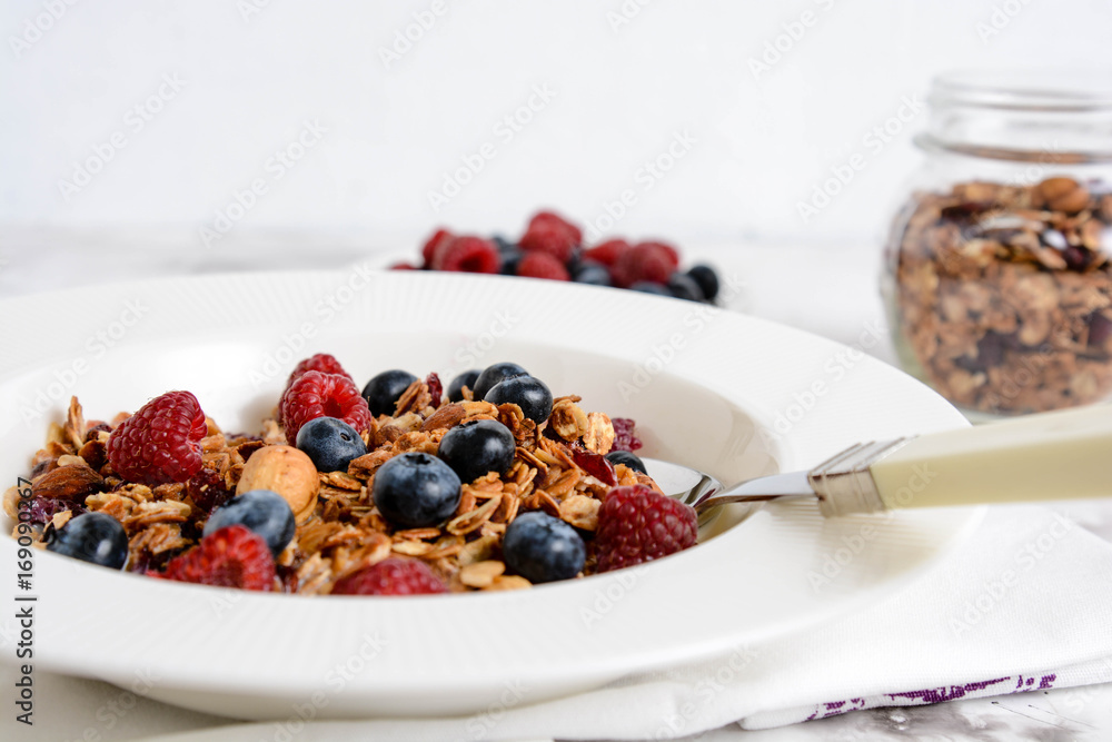 Healthy breakfast in a bowl with homemade baked granola, fresh berries and yogurt on a marble table. Healthy breakfast in a bowl with homemade baked granola, fresh berries and yogurt on a marble table.