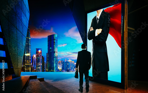 Young businessman looking the hero businessman on the advertising billboard screen . Successful businessman concept . photo