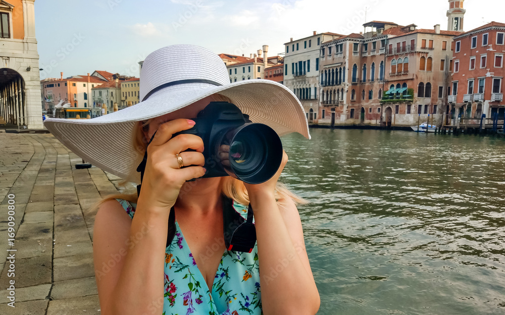 Close-up portrait of attractive woman taking pictures with her camera while discovering Venice.