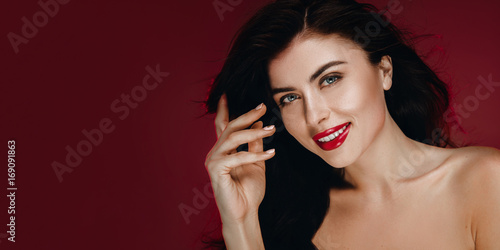 Beauty Brunette Woman with Perfect Makeup. Beautiful Professional Holiday Make up. Beauty Girl  Face  studio portrait isolated on red background