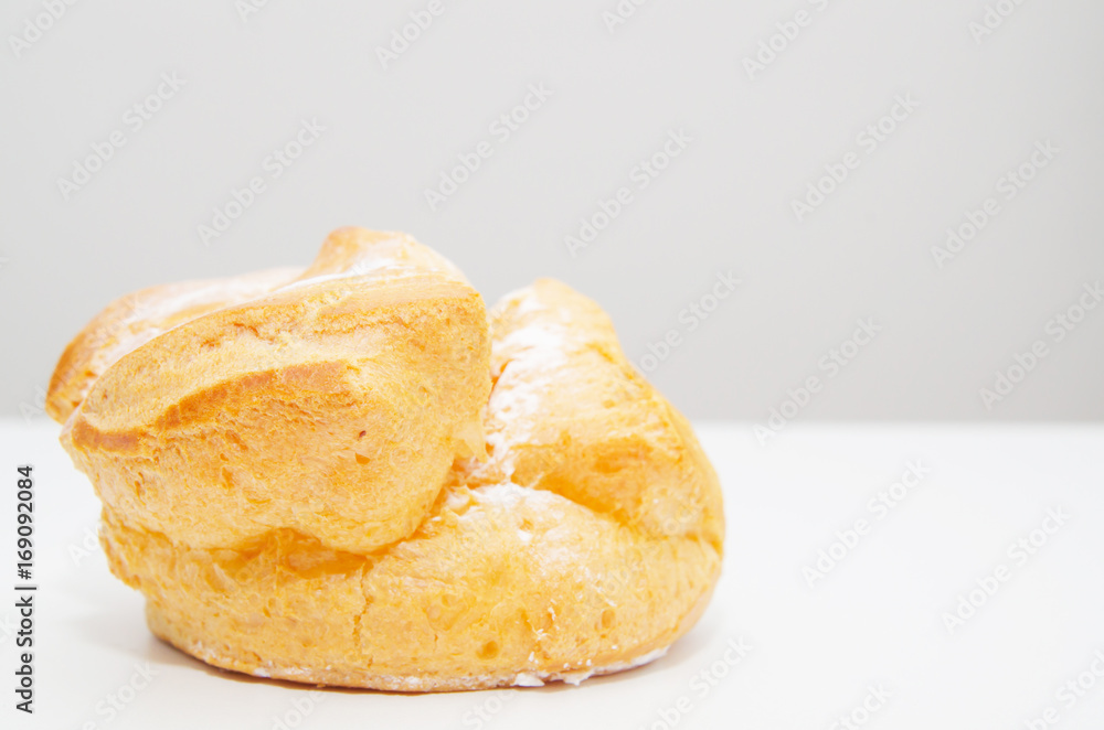 Profiteroles stuffed with pastry cream on white desk in cafe Profiteroles stuffed with pastry cream on white desk in cafe