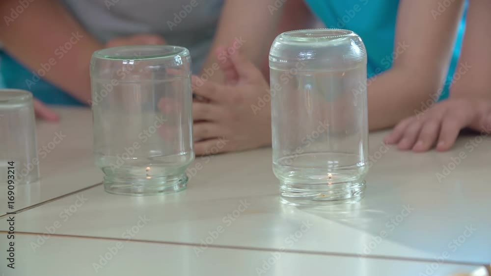 Three bottles are on the table and they are standing upside down. There is a small candle underneath each of them. Three bottles are on the table and they are standing upside down. There is a small candle underneath each of them.