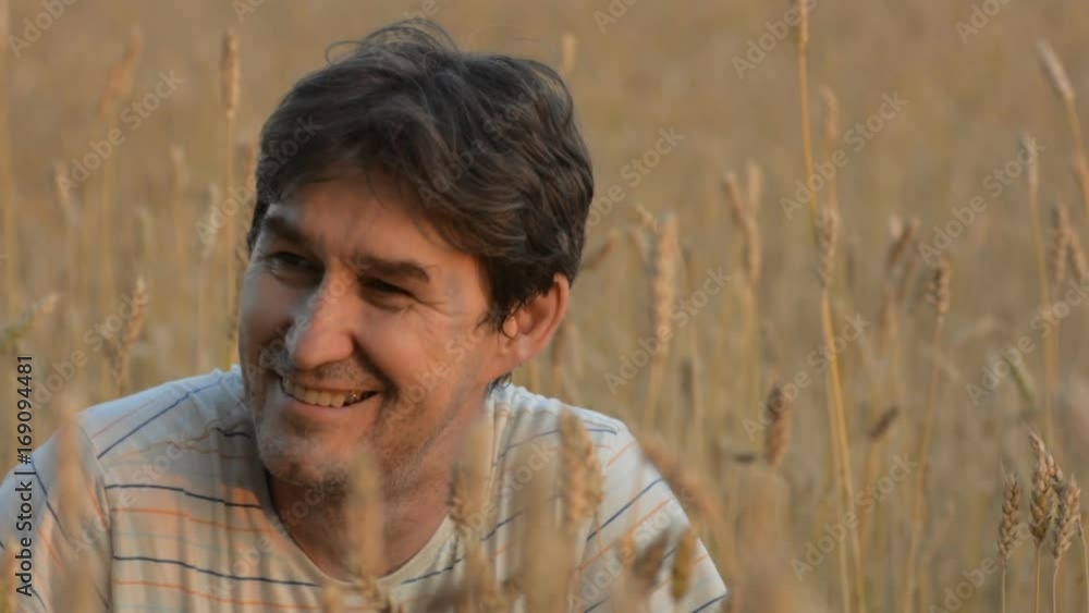 Cheerful farmer on the wheat field. Close-up portrait of an adult male against a ripe crop of cereals Cheerful farmer on the wheat field. Close-up portrait of an adult male against a ripe crop of cereals