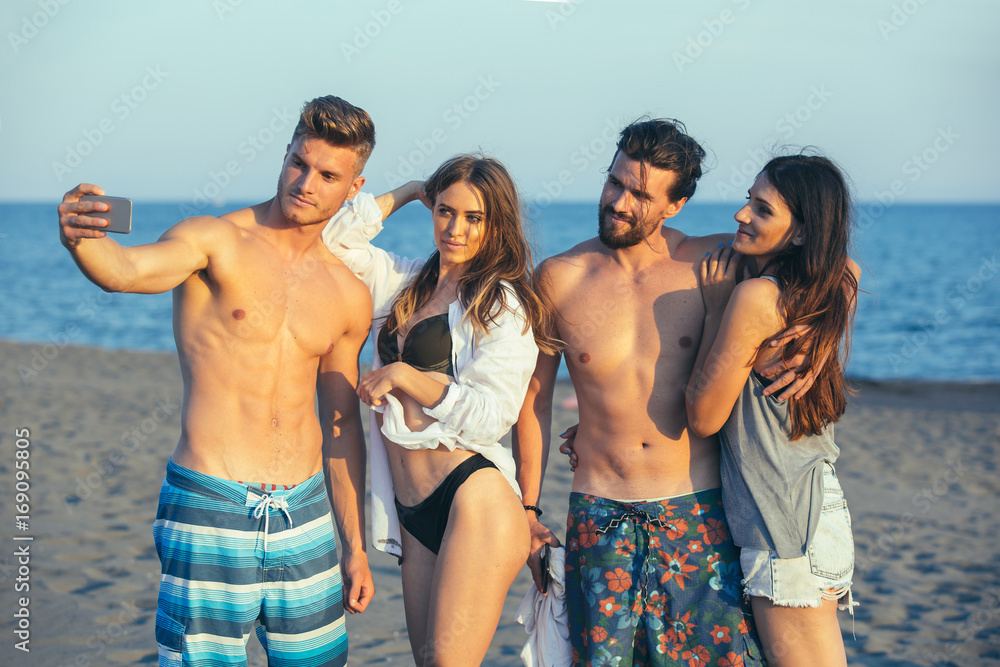 Cheerful friends taking selfie at beach on sunny day Cheerful friends taking selfie at beach on sunny day