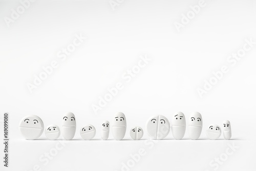 Funny white tablets in a row, various shapes, 12 pieces, white background, 