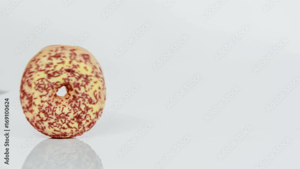 A doughnut is slowly rolling down the table in the kitchen. A doughnut is slowly rolling down the table in the kitchen.