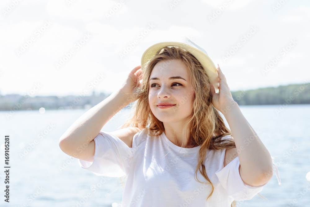 Portrait of a beautiful young blonde girl in hat, outdoors