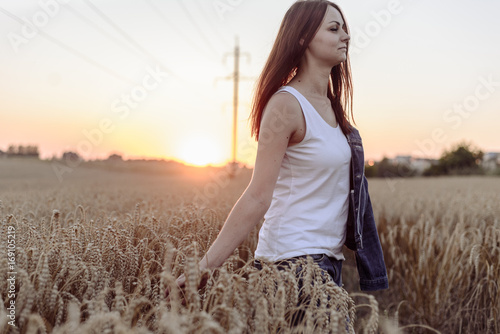 Portrait of happy young beautiful woman brunette in field wheat sunset evening