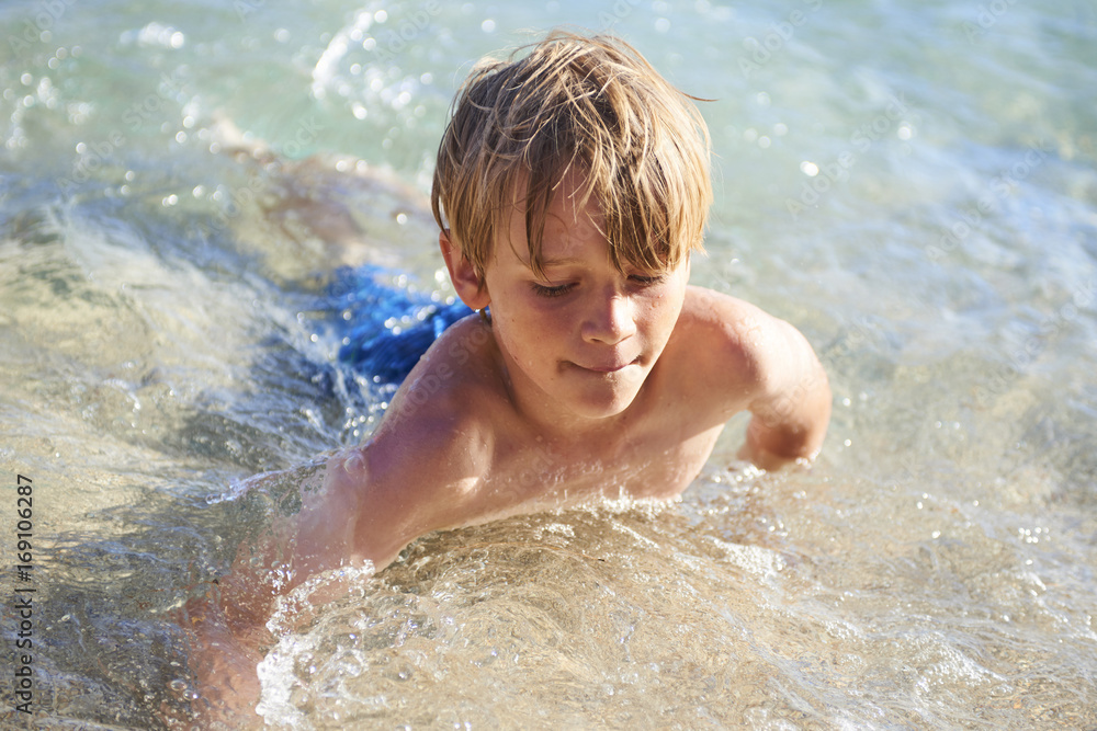 Young child boy having fun in the sea on the waves and enjoying water in summer holiday Young child boy having fun in the sea on the waves and enjoying water in summer holiday