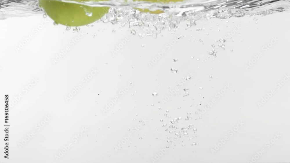 Slo-motion two green apples falling into water Slo-motion two green apples falling into water