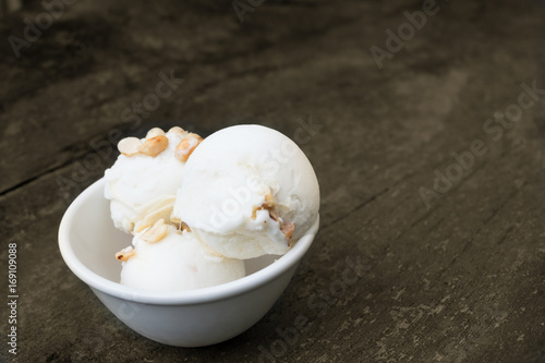 Coconut ice cream in white bowl on old wood background