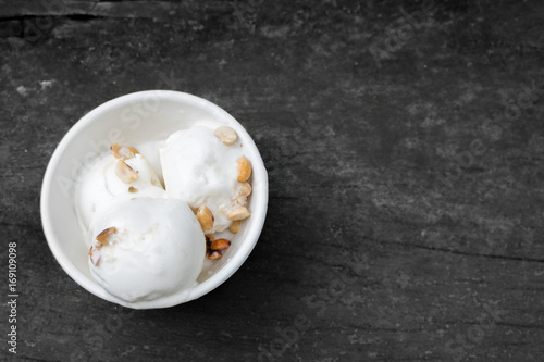 Coconut ice cream in white bowl on old wood background
