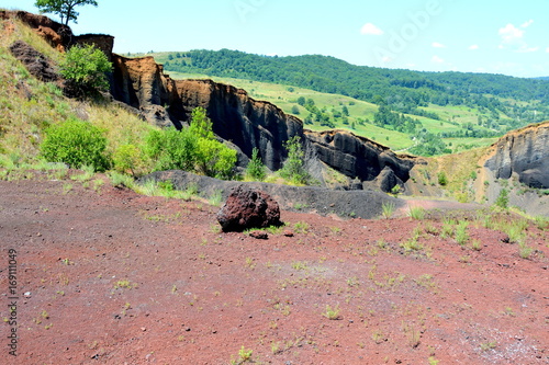 Abandoned career of red scorea rocks. Racos is a village in Brasov county, Transylvania, Romania near one active and three abandoned stone career. It is a national protected area photo