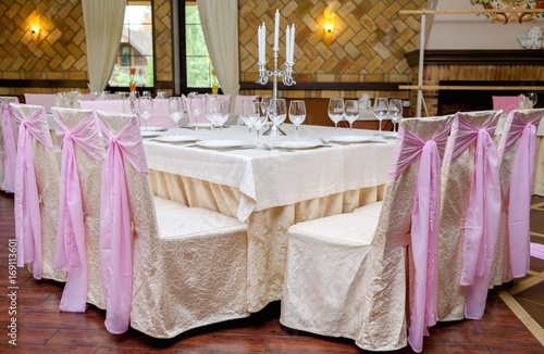 Chairs with beige and pink cloth and table for guests served for wedding banquet. Dinner table for wedding banquet. Table setting